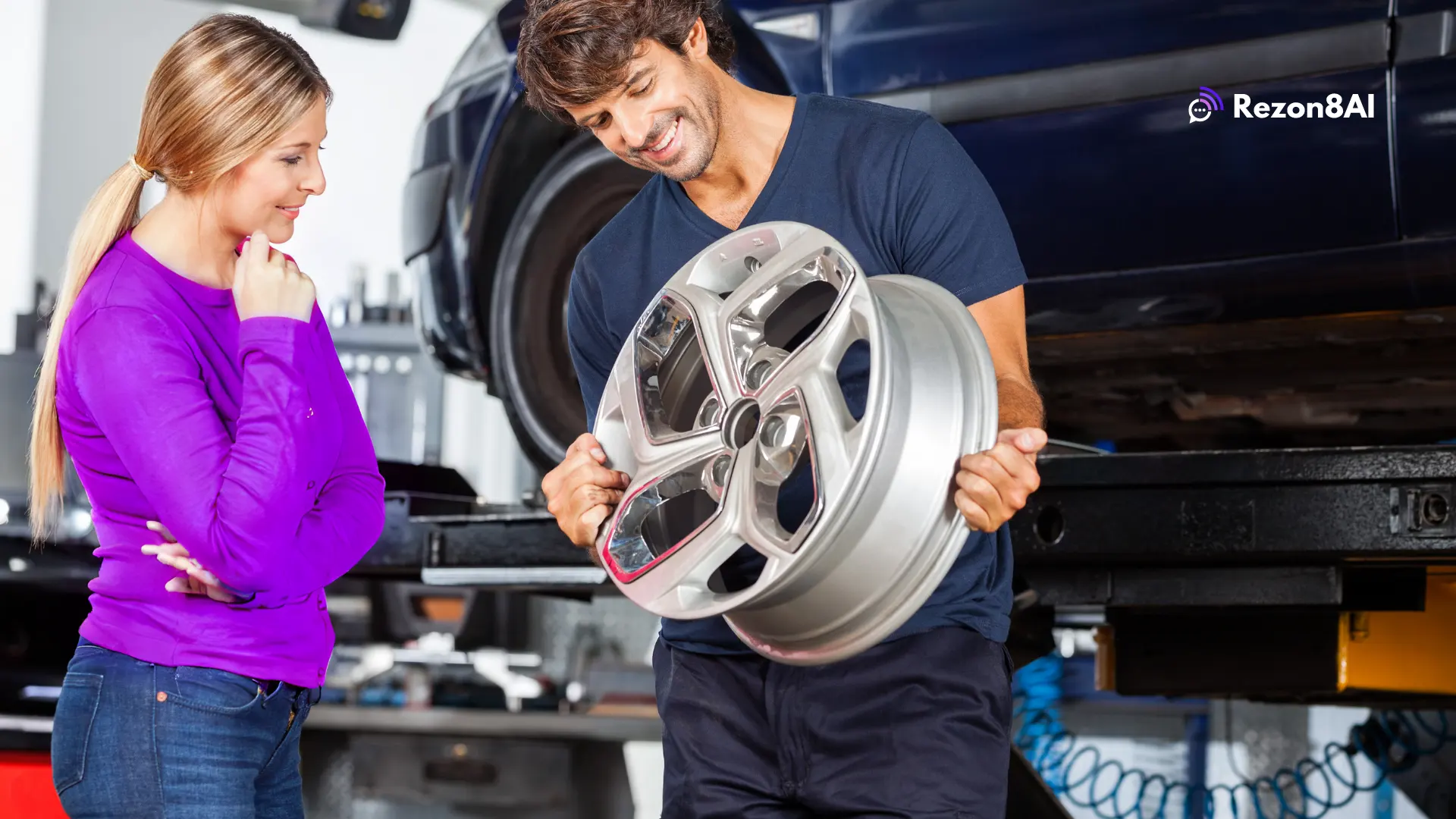 A mechanic holding a car rim showing it to a female customer in an auto repair shop.